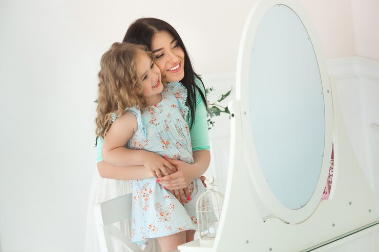 Filha pequena e sua mãe aplicando compõem um ao outro. Mãe muito jovem e adorável garota se divertindo juntos. Família fashionista bonita