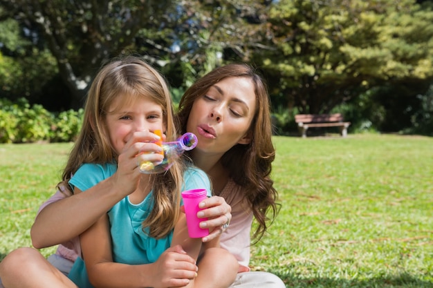 Filha sorridente com mãe fazendo bolhas