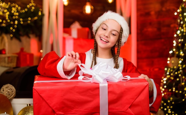 Foto filha trocando presente cena de natal com árvore e presentes clima de natal celebração de férias em família feliz ano novo de criança santa com caixa de presente venda de compras de inverno tendo fu