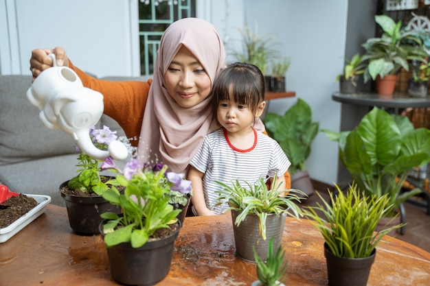 Filha vê a mãe segurando um regador enquanto rega as plantas