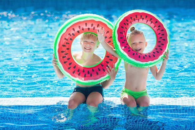 Filhinhos bonitos perto da piscina. Crianças se divertindo no verão.