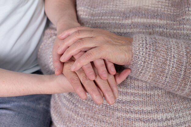 Filho adulto segurando as mãos das mães mais velhas em casa Homem de apoio segurando a mão das avós