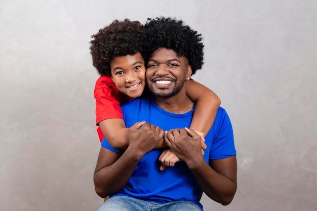 Filho afro abraçando seu pai em fundo neutro com espaço livre para texto