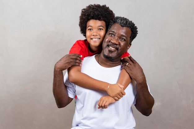 Filho afro abraçando seu pai em fundo neutro com espaço livre para texto