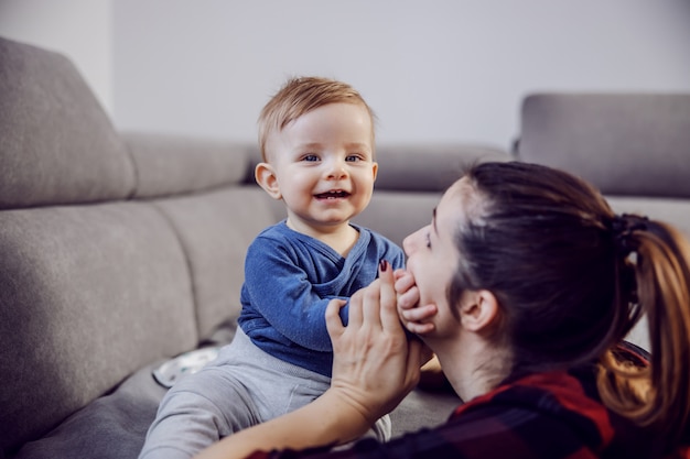 Filho amado feliz sentado no sofá e brincando com sua mãe.