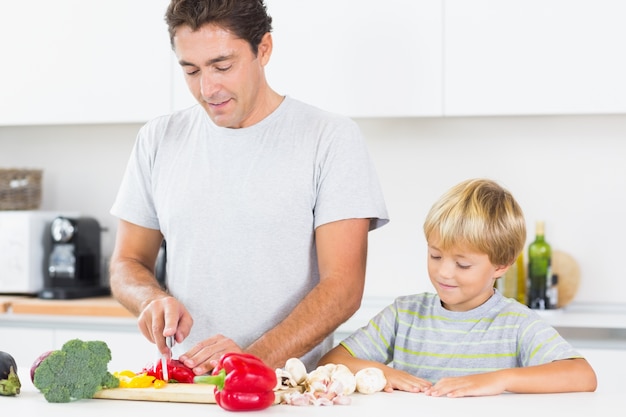 Filho assistindo pai preparando legumes