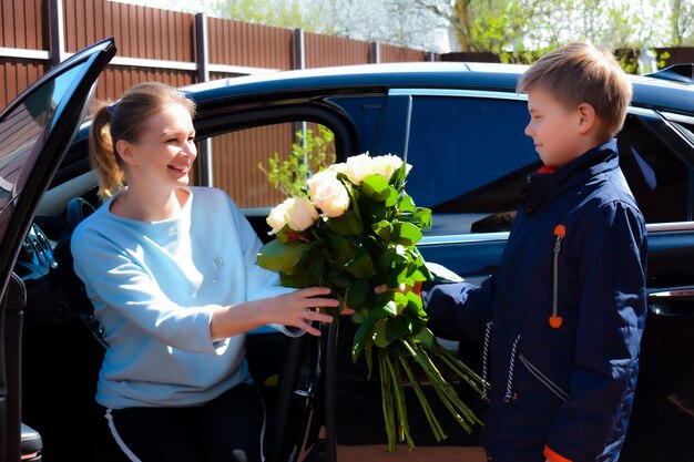 Filho dá um buquê de rosas para a mãe Mãe feliz com filho filho