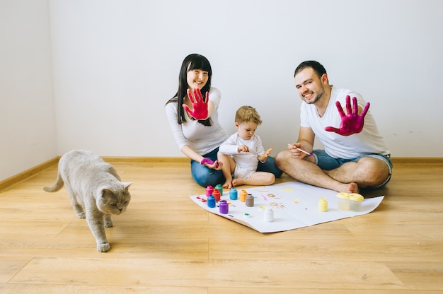 filho de família feliz com os pais e um gato pintando um cartaz