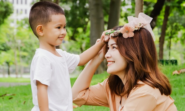 Filho de retrato usando linda coroa de flores para a mãe com amor no jardim lindo tempo.