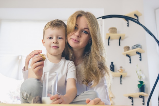 Filho e mãe bebem leite. a mãe abraça o bebê antes do café da manhã.