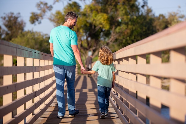 Filho feliz esticando as mãos pai vista traseira homem bonito e menino bonito ao ar livre