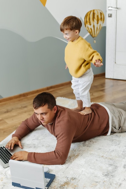 Filho fica de costas do pai no chão com computadores Pai ensina seu filho a programar