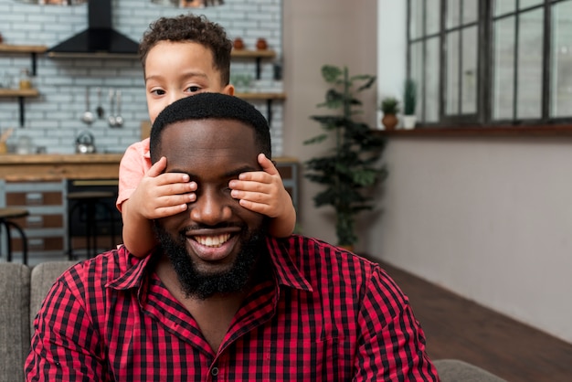 Filho negro, cobrindo os olhos do pai