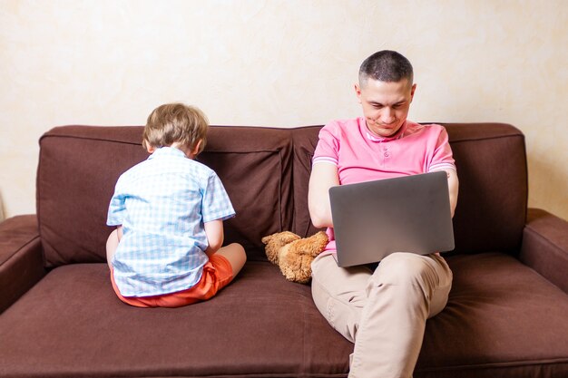 Filho ofendido com o pai ocupado com laptop