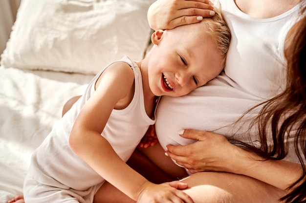 Filho pequeno e mãe grávida se abraçam