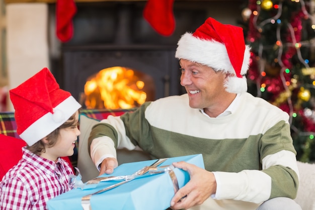 Filho que dá ao pai um presente de natal no sofá