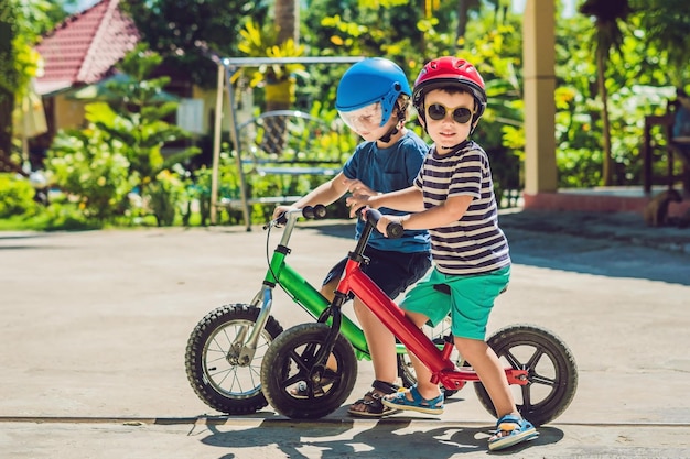 Filhos de dois meninos se divertindo na Balance Bike em uma estrada tropical.