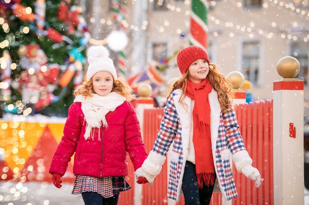 Filhos de irmãs ruivas caminham em um mercado de Natal festivamente decorado na cidade.