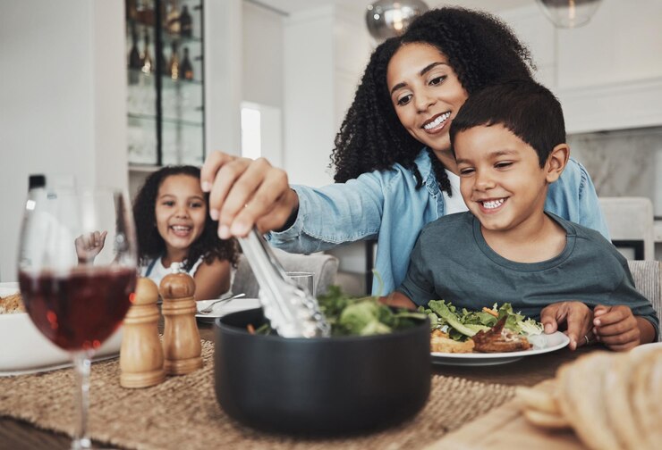 Foto filhos de mãe e comendo comida em casa juntos para almoço mesa de jantar e refeição saudável mãe de família feliz e filhos sorriem para jantar em casa com amor, cuidado e felicidade de um jantar delicioso