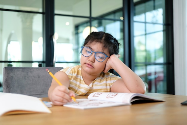 Filhos de menina bonitos e felizes usando o computador portátil, estudando através do sistema de e-learning on-line.