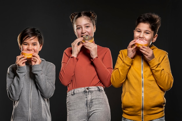 Foto filhos de tiro médio comendo donuts