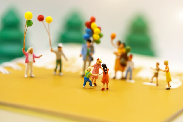 Filhos e família em miniatura de pessoas desfrutam com balões coloridos.