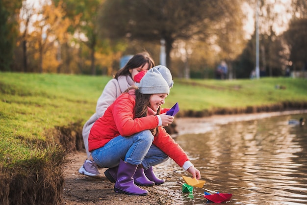 Filhos e mãe brincando com barquinhos de papel no lago