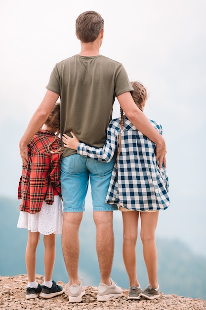 Filhos lindos e homem feliz nas montanhas ao fundo do nevoeiro