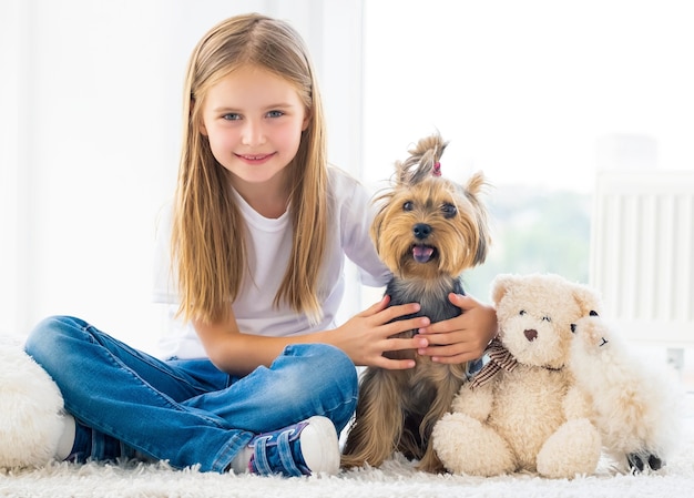 Filhote de cachorro terrier e menina feliz sentados dentro de casa