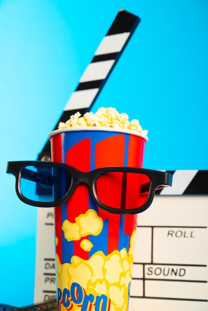Foto film clapper pop corn óculos 3d e bobina de filme em fundo azul design de colagem