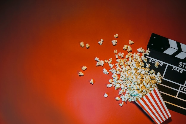 Foto film mit popcorn auf rotem hintergrund draufsicht ansehen.