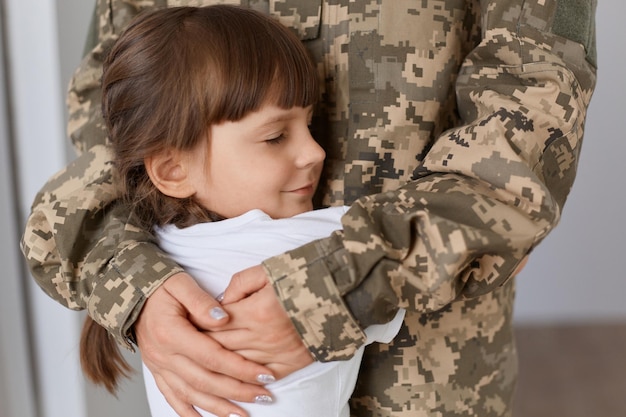 Filmación en interiores de una linda chica encantadora abrazando a su madre que viene después de la guerra o del ejército, una mujer anónima vestida con uniforme militar abrazando a su hijo con amor.