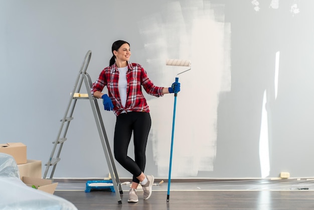 Filmación en interiores de una mujer morena mirando a otro lado y sonriendo mientras va a pintar con equipo de reparación de rodillos en sus nuevos apartamentos