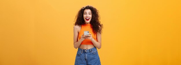 Foto filmación en interiores de sorprendida feliz y encantada atractiva mujer europea con corte de pelo rizado en croppe