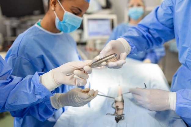 Filmado na sala de cirurgia Assistente entrega instrumentos para cirurgiões durante a operação Cirurgiões realizam a operação Médicos profissionais realizando cirurgia