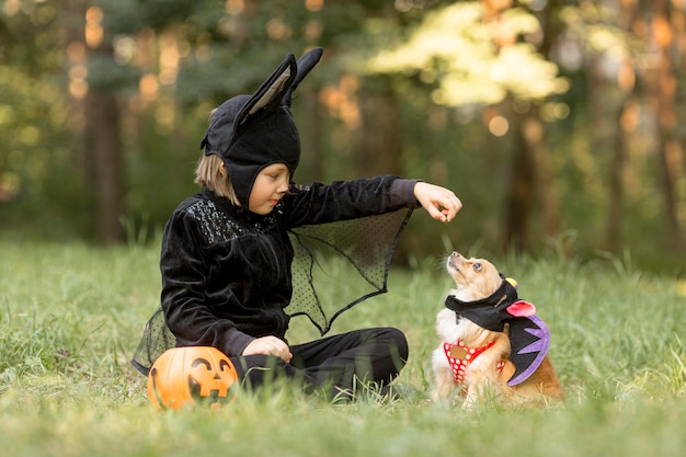 Foto filmagem de um menino com fantasia de morcego e cachorro