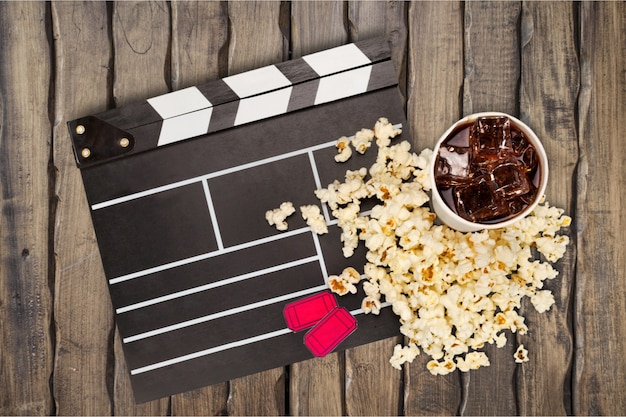 Filmclipper, Popcorn und Limonade in der Tasse auf Holzbohlenhintergrund. Filmzeitkonzept