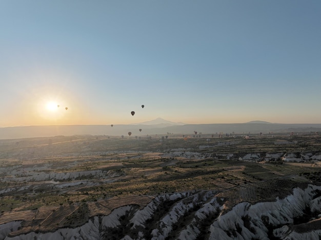 Filmische Drohnenansicht eines farbenfrohen Heißluftballons, der über Kappadokien fliegt