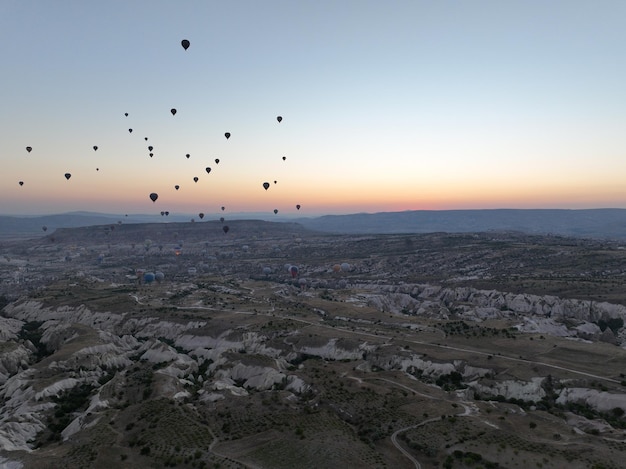 Filmische Drohnenansicht eines farbenfrohen Heißluftballons, der über Kappadokien fliegt