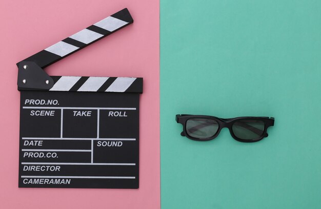 Filmklappe mit 3D-Brille auf rosa blauem Pastellhintergrund. Kino, Filmemachen, Filmproduktion, Unterhaltungsindustrie. Ansicht von oben