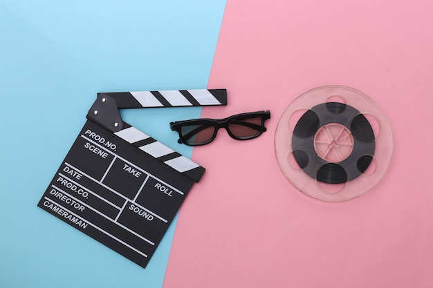 Filmklappe und Filmrolle, 3D-Brille auf rosa blauem Pastellhintergrund. Kinoindustrie, Unterhaltung. Ansicht von oben