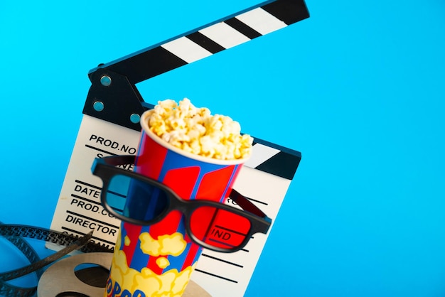 Filmklapper Popcorn 3D-Brille und Filmrolle auf blauem Hintergrund Collagen-Design