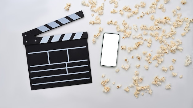 Filmschindel und Popcorn mit leerem Bildschirm des Smartphones auf weißem Hintergrund.