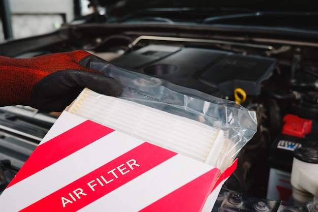 Un filtro de aire nuevo en su caja está siendo retenido por la mano de un técnico de automóviles