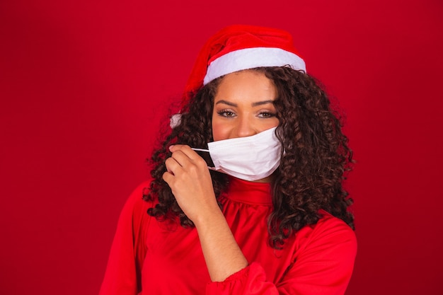 Fim da pandemia no Natal. Mulher tirando a máscara com chapéu de Papai Noel