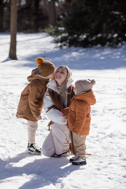 Fim de semana de inverno Mãe e dois filhos em roupas de inverno quentes caminhando enquanto se divertem na floresta de inverno entre as árvores