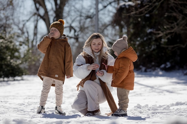 Fim de semana de inverno Mãe e dois filhos em roupas de inverno quentes caminhando enquanto se divertem na floresta de inverno entre as árvores