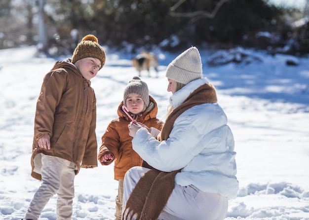 Fim de semana de inverno Mãe e dois filhos em roupas de inverno quentes caminhando enquanto se divertem na floresta de inverno entre as árvores