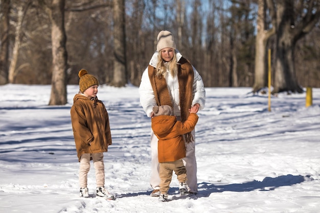 Fim de semana de inverno Mãe e dois filhos em roupas de inverno quentes caminhando enquanto se divertem na floresta de inverno entre as árvores