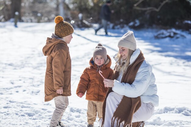 Fim de semana de inverno Mãe e dois filhos em roupas de inverno quentes caminhando enquanto se divertem na floresta de inverno entre as árvores